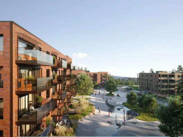 Moderne boligblokker med trefasader vender ut mot en anlagt gårdsplass med trær, gangstier og mennesker som nyter uterommet på en solrik dag.