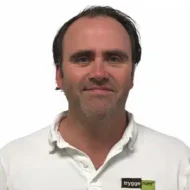 Christoffer-Viig En mann med kort, mørkt hår og hvit skjorte med "trygge rom"-logo står mot en hvit bakgrunn.