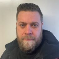 Fredrik-Bergli-Hagen-e1618558409981-300x300 En mann med lys hud, kort brunt hår og helskjegg er iført mørk jakke og ser inn i kameraet mot en ensfarget bakgrunn.