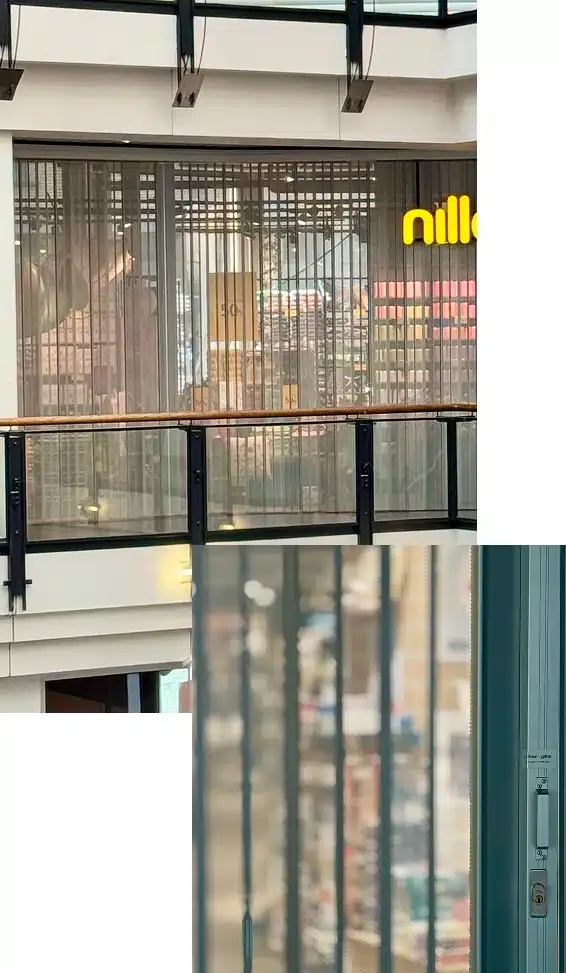 Group-12 Utsikt over en lukket butikkfasade med vertikale metallgitter i et kjøpesenter; en del av et gult "nille"-skilt er synlig bak gitteret.