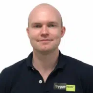 Jonas-Berntsen-Kvalen-300x300 En mann med barbert hode og svart polo med "tryggerom"-logo står mot en hvit bakgrunn.