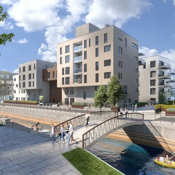 Moderne boligblokker ligger langs en kanal med en gangbro. Folk går på stier, og to personer padler kajakk i vannet under en delvis overskyet himmel.