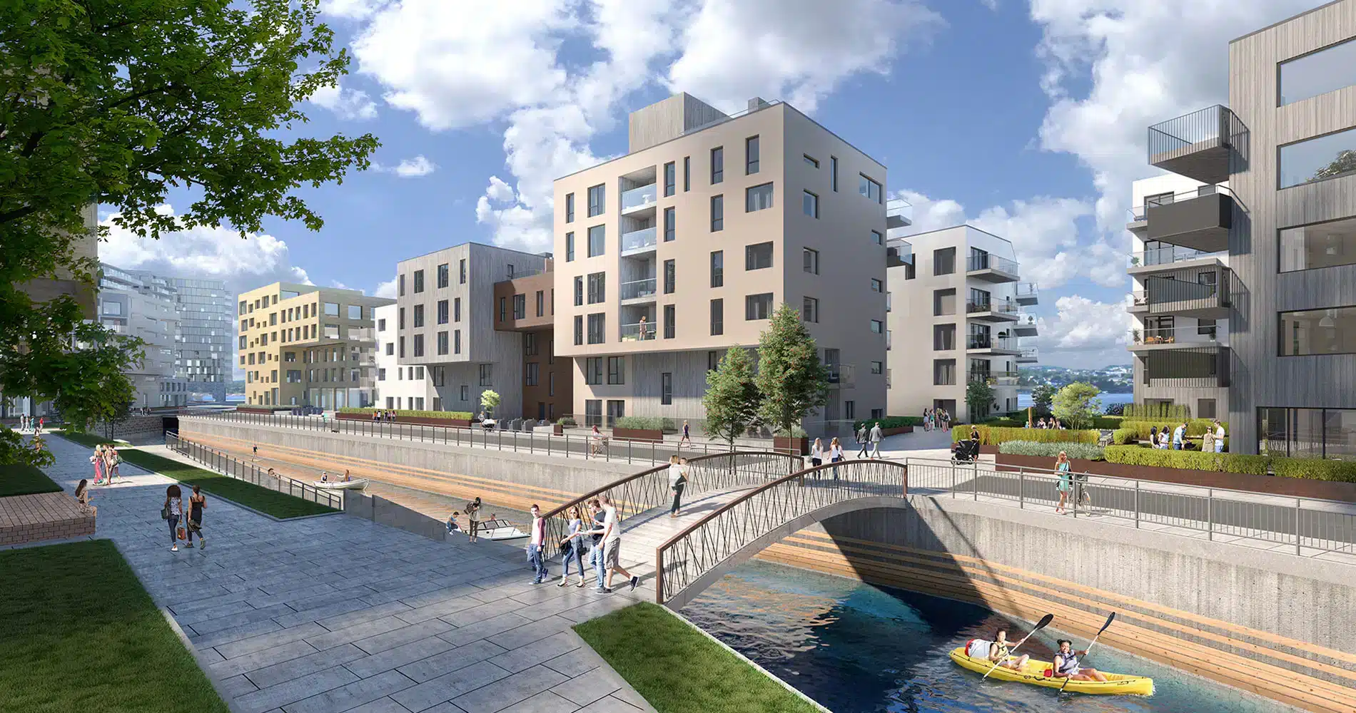 Moderne boligblokker ligger langs en kanal med en gangbro. Folk går på stier, og to personer padler kajakk i vannet under en delvis overskyet himmel.