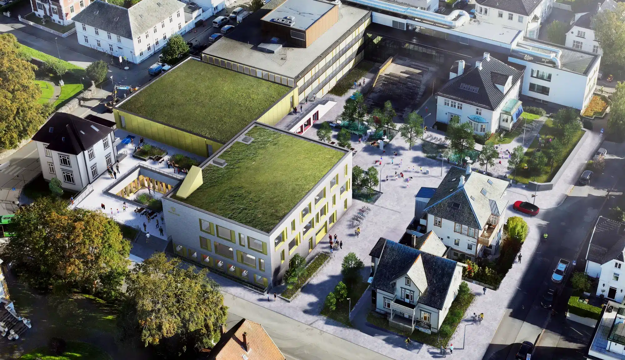 Luftfoto av et bykvartal med moderne bygninger med grønne tak side om side med eldre hus og et sentralt torg med fotgjengere.