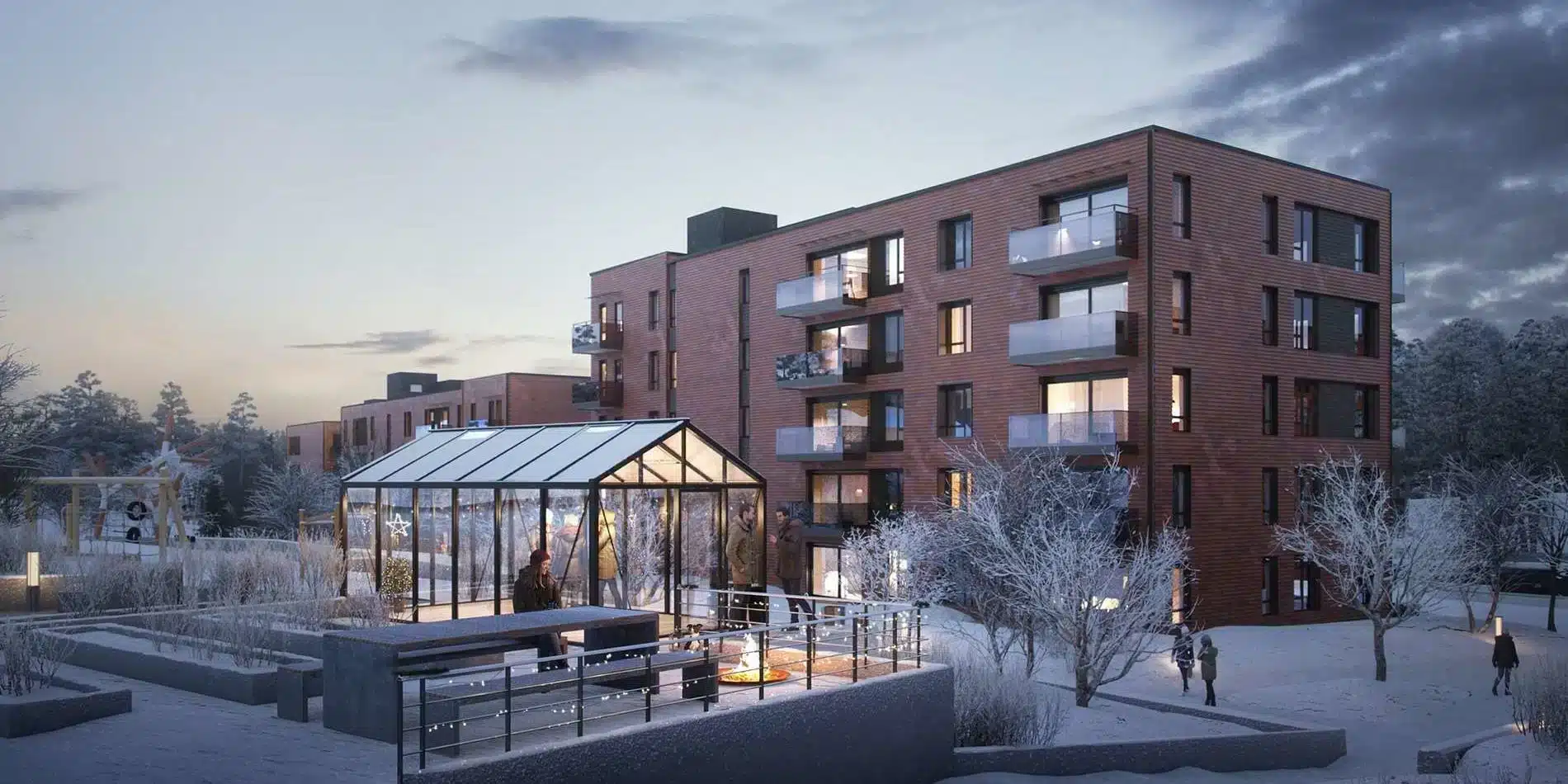 Moderne leilighetskompleks med balkonger, ved siden av et drivhus med glassvegger og uteservering, omgitt av snødekte trær og stier i skumringen.