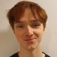teodor-300x300 En ung person med kort, rufsete rødbrunt hår står foran en strukturert hvit vegg, ser inn i kameraet og smiler lett.